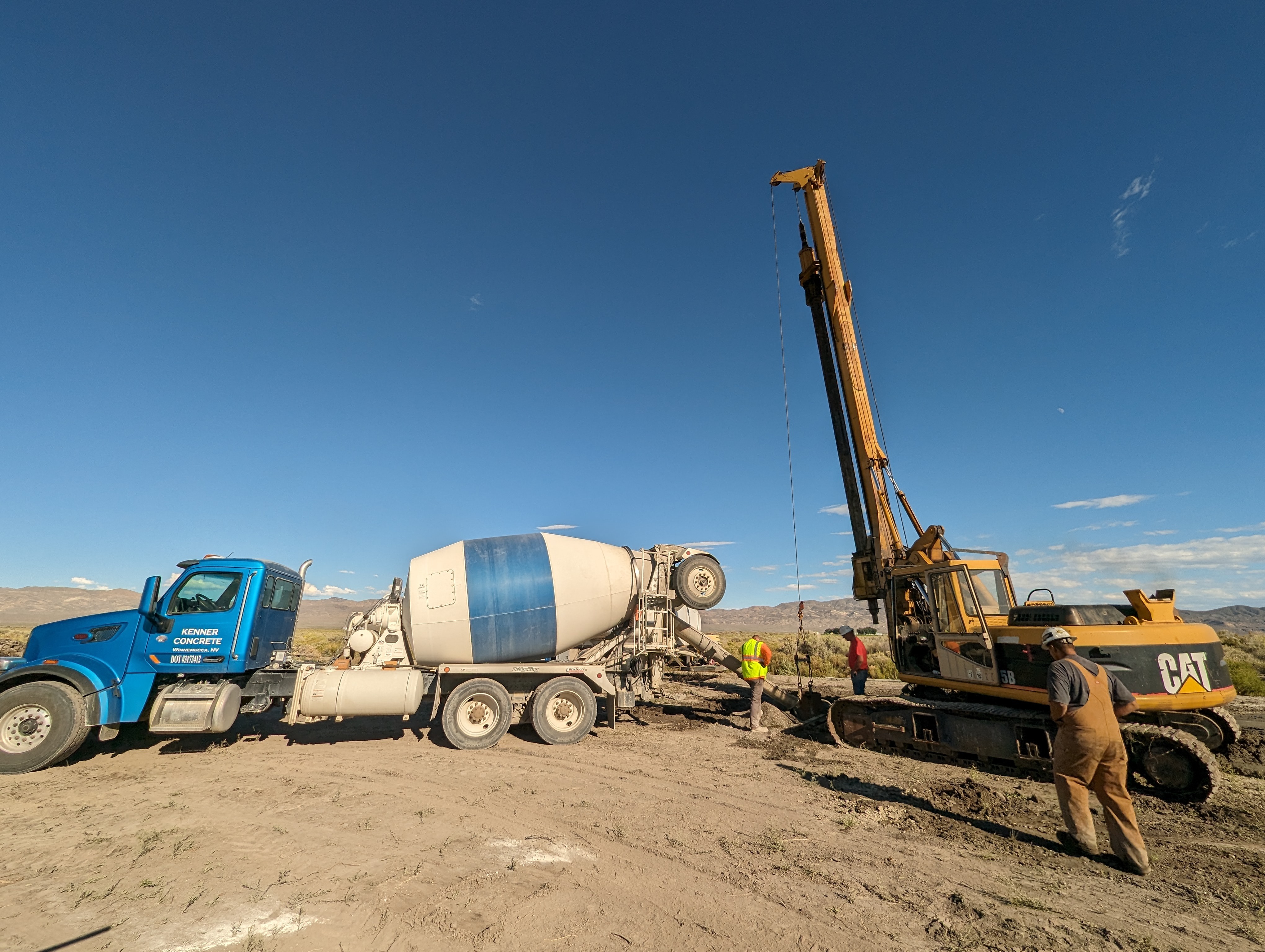 Workers operating a cement truck and crane